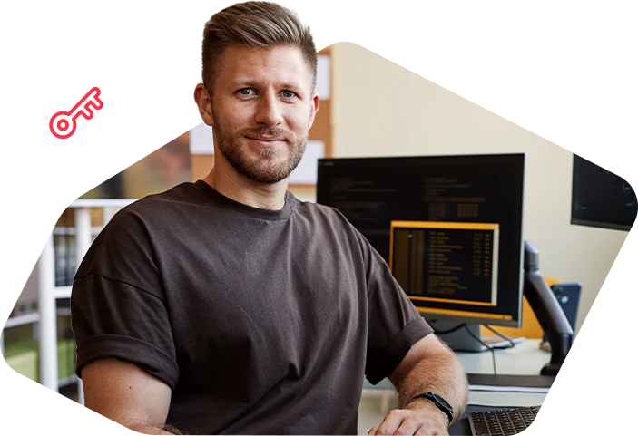 Man in a brown shirt sitting at a desk with computer screens in a modern office setting Man in a brown shirt sitting at a desk with computer screens in a modern office setting