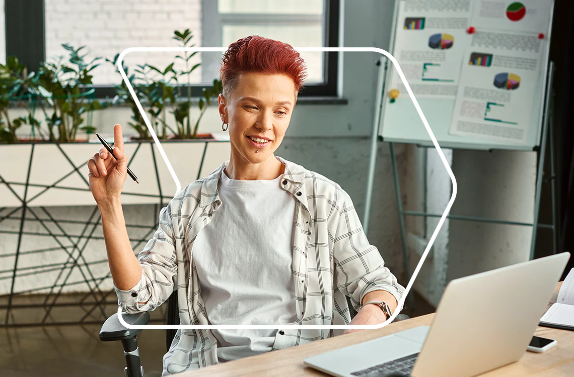 Woman with short red hair participating in an online meeting, holding a pen, with charts in the background. Woman with short red hair participating in an online meeting, holding a pen, with charts in the background.