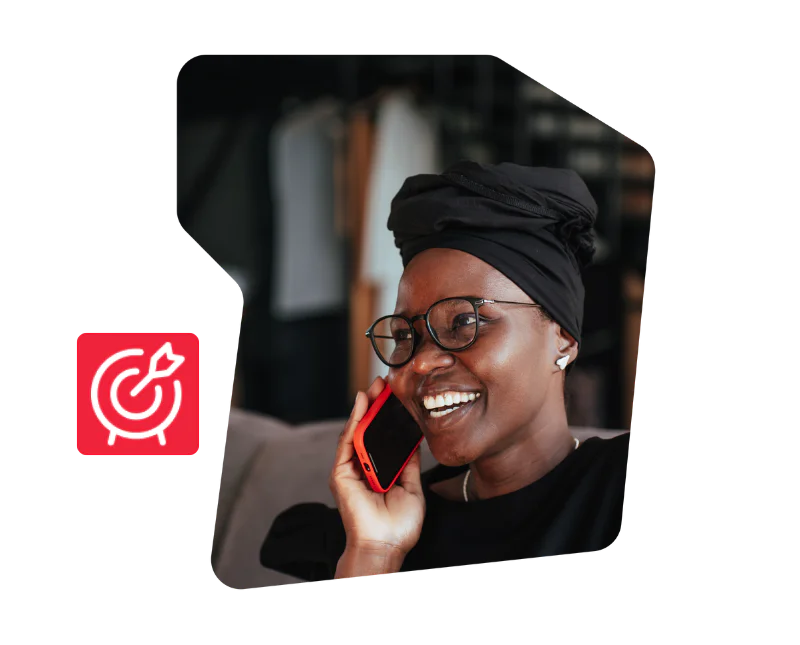 Woman wearing glasses and a headwrap, smiling while talking on a red phone