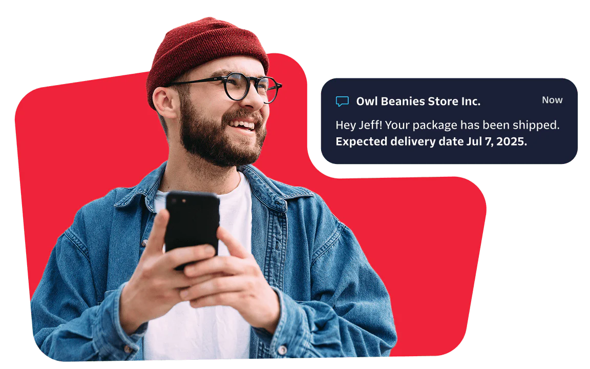 Smiling man with a red beanie checks his phone for a message about his package delivery.